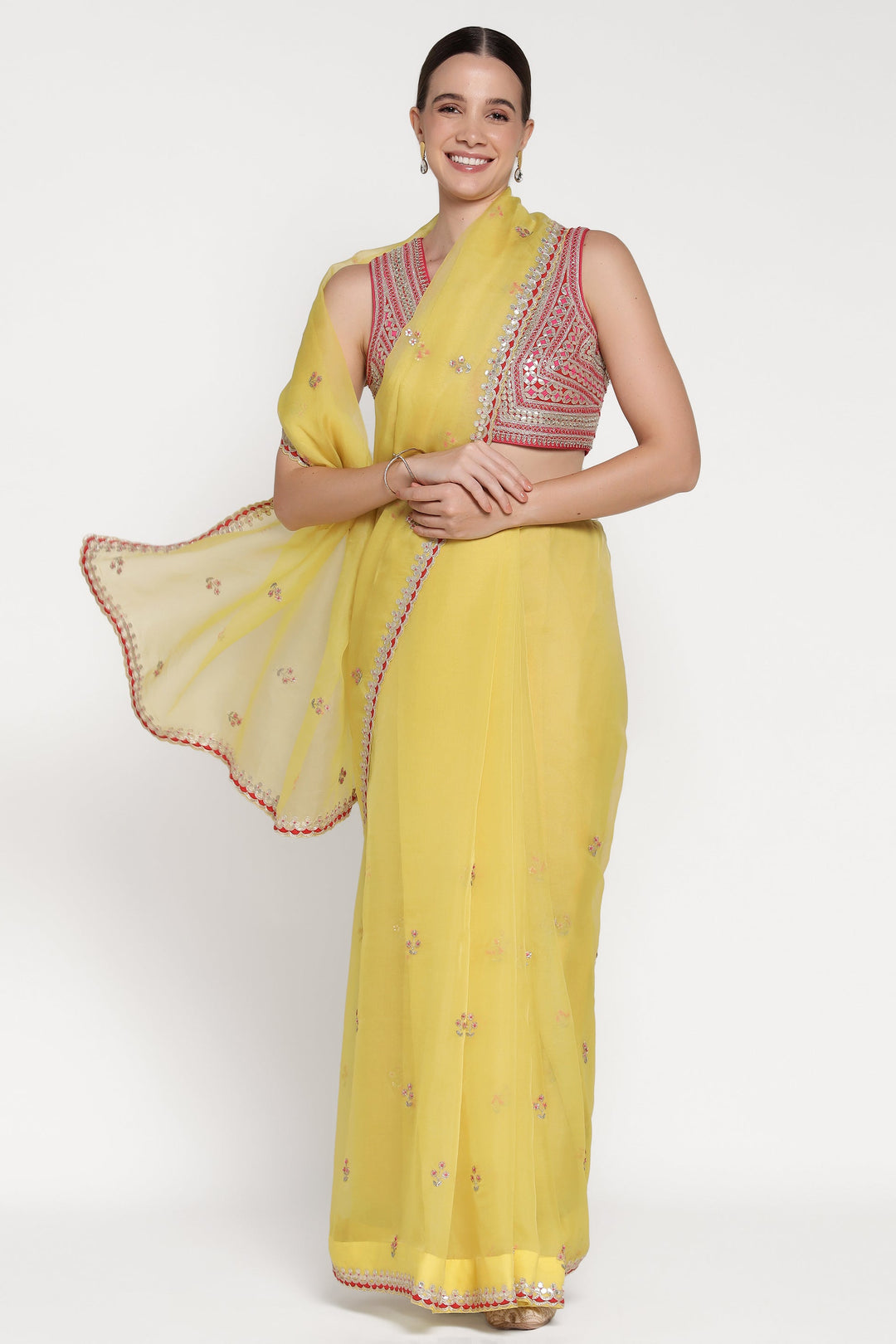 Woman wearing a yellow saree with a red blouse on a white background
