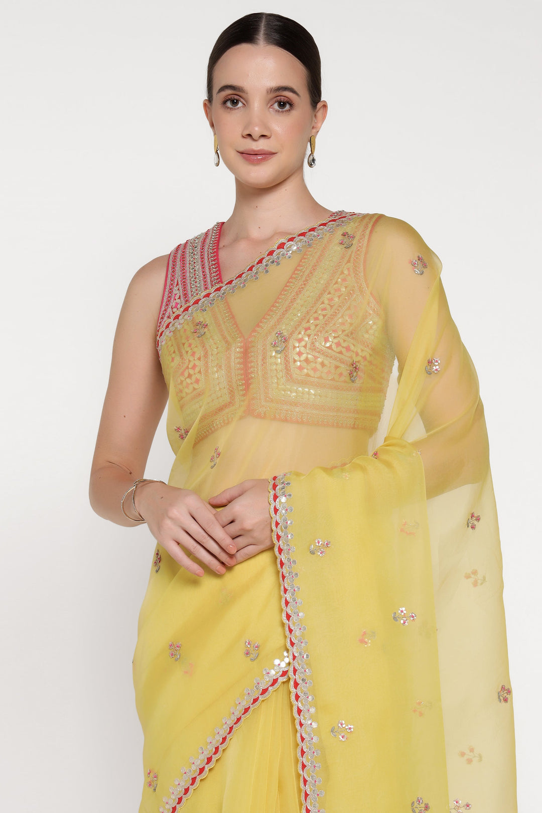 Woman wearing a yellow saree with intricate designs on a white background