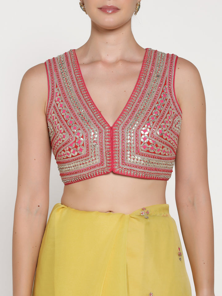 Woman wearing a pink embroidered top with a plain background