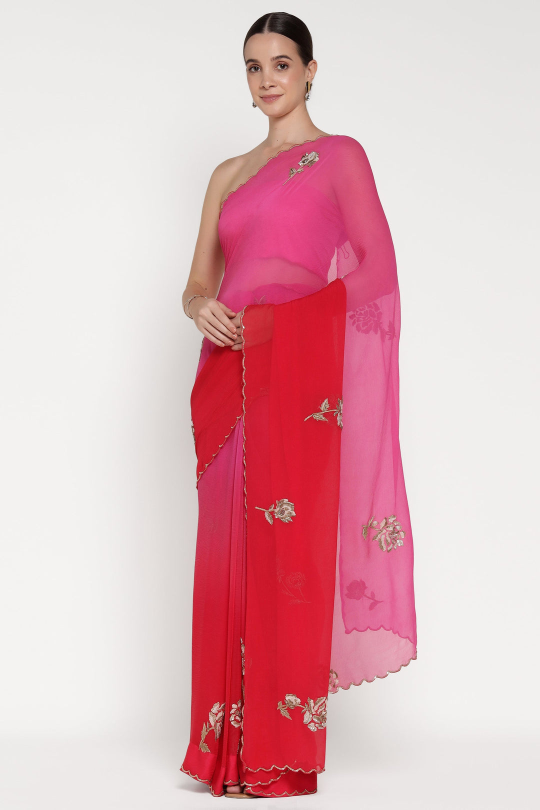 Woman wearing a red and pink saree with floral patterns on a white background