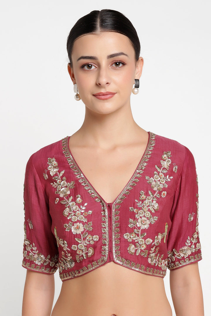 Woman wearing a maroon blouse with floral embroidery on a white background