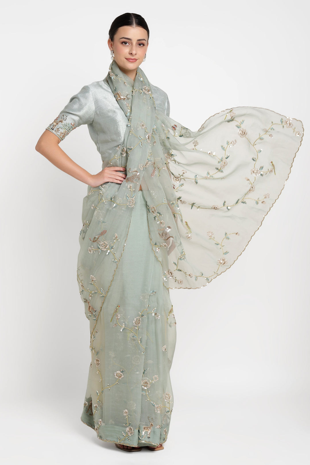 Woman wearing a light green saree with floral patterns on a white background