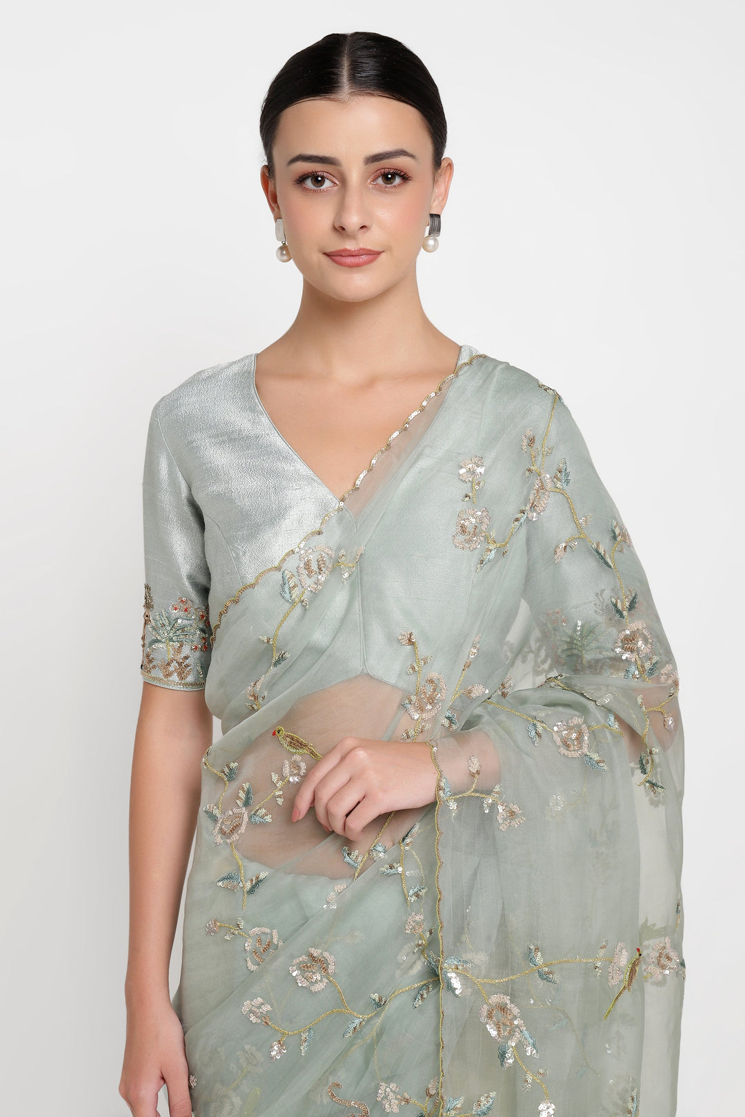 Woman wearing a light green saree with floral embroidery on a white background