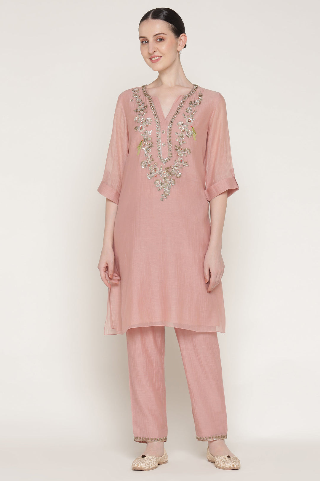 Woman wearing a pink embroidered outfit on a white background