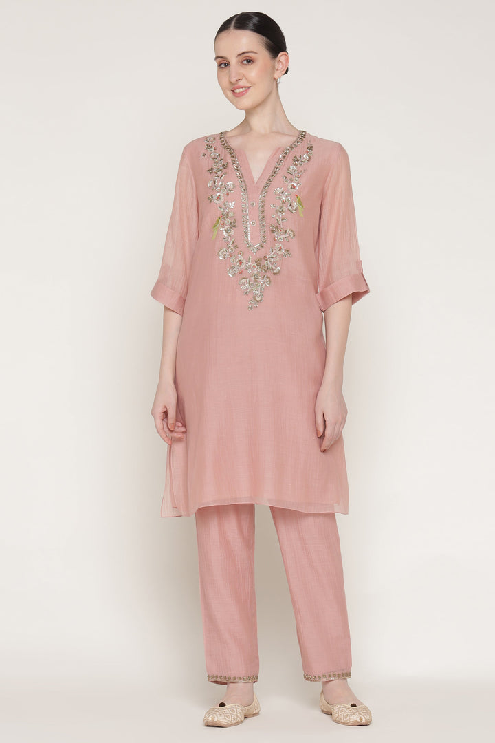 Woman wearing a pink embroidered outfit on a white background