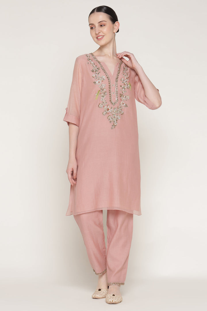 Woman wearing a pink traditional outfit with embellishments on a white background