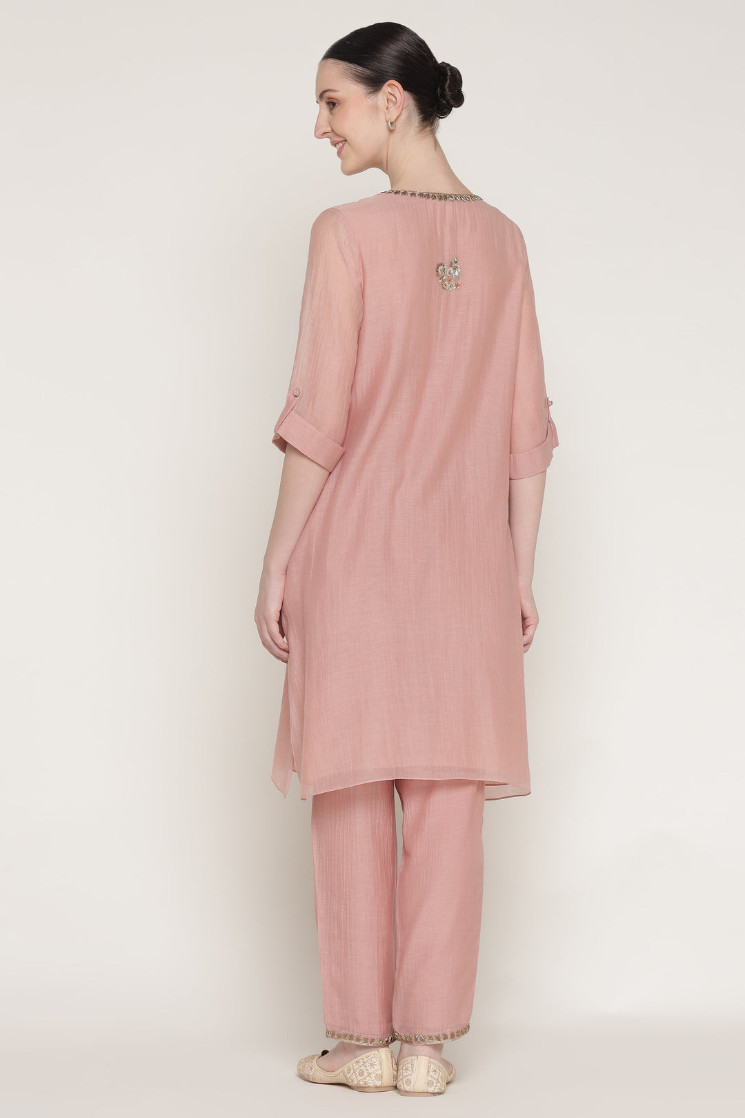 Woman wearing a pink traditional outfit with a plain background