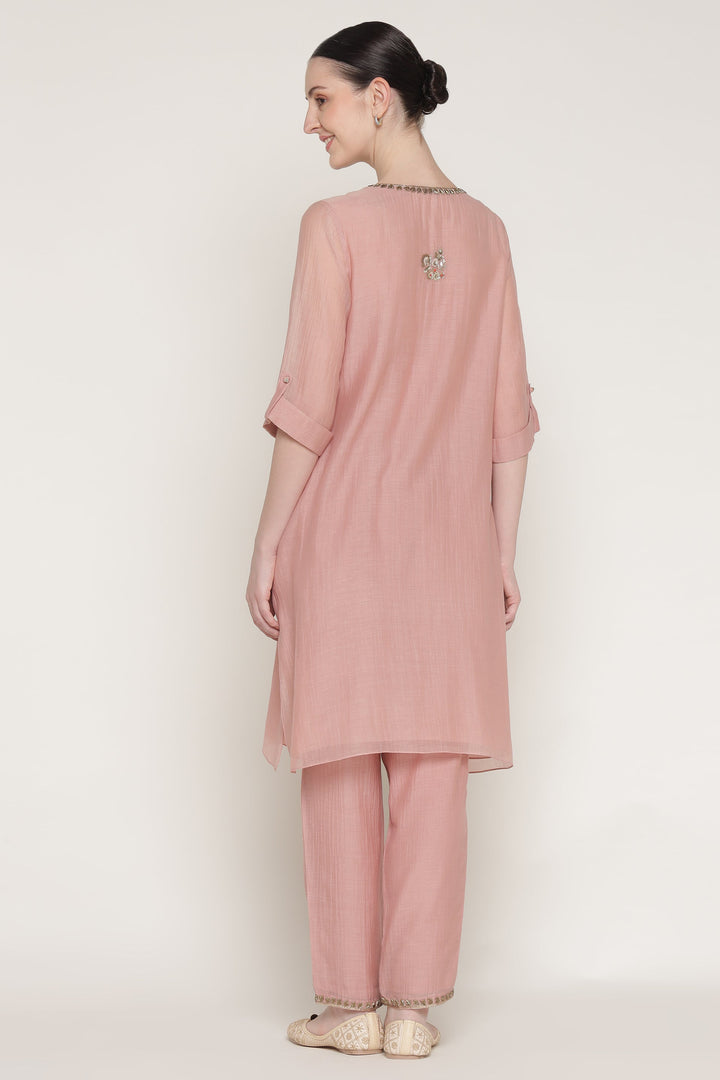 Woman wearing a pink traditional outfit with a plain background