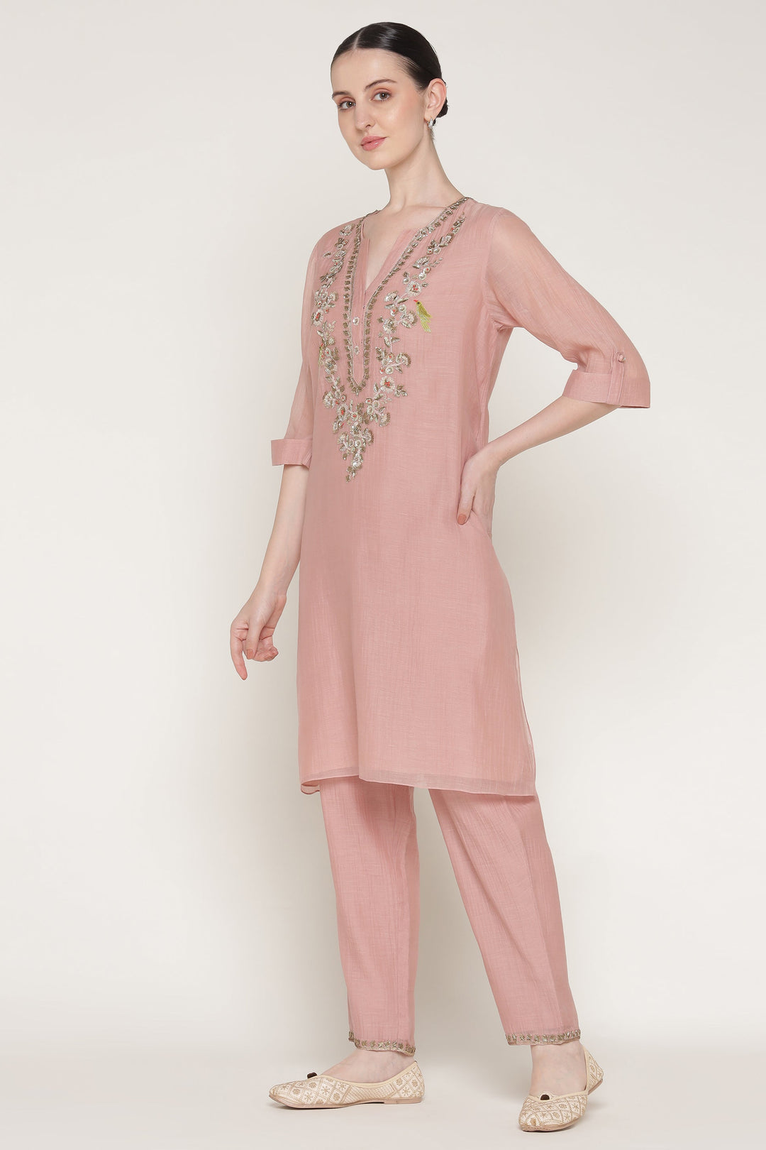 Woman wearing a pink traditional outfit with intricate designs on a white background