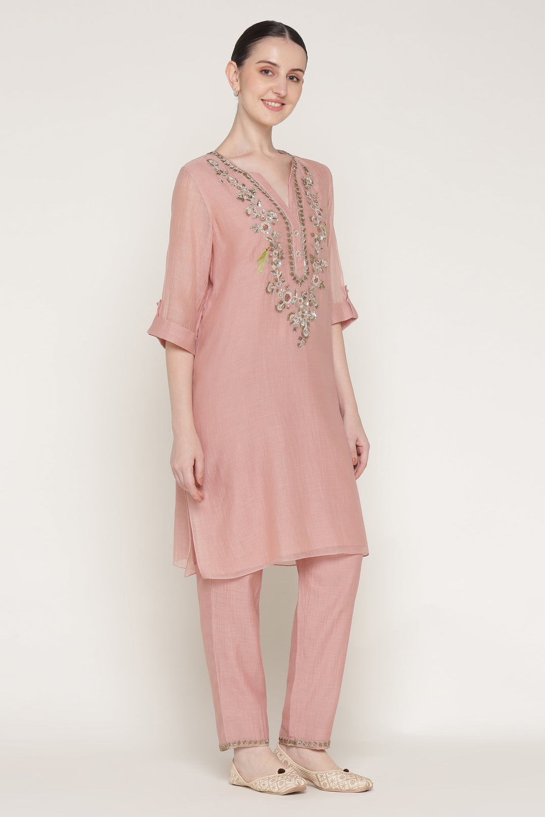 Woman wearing a pink kurta with embroidery on a white background