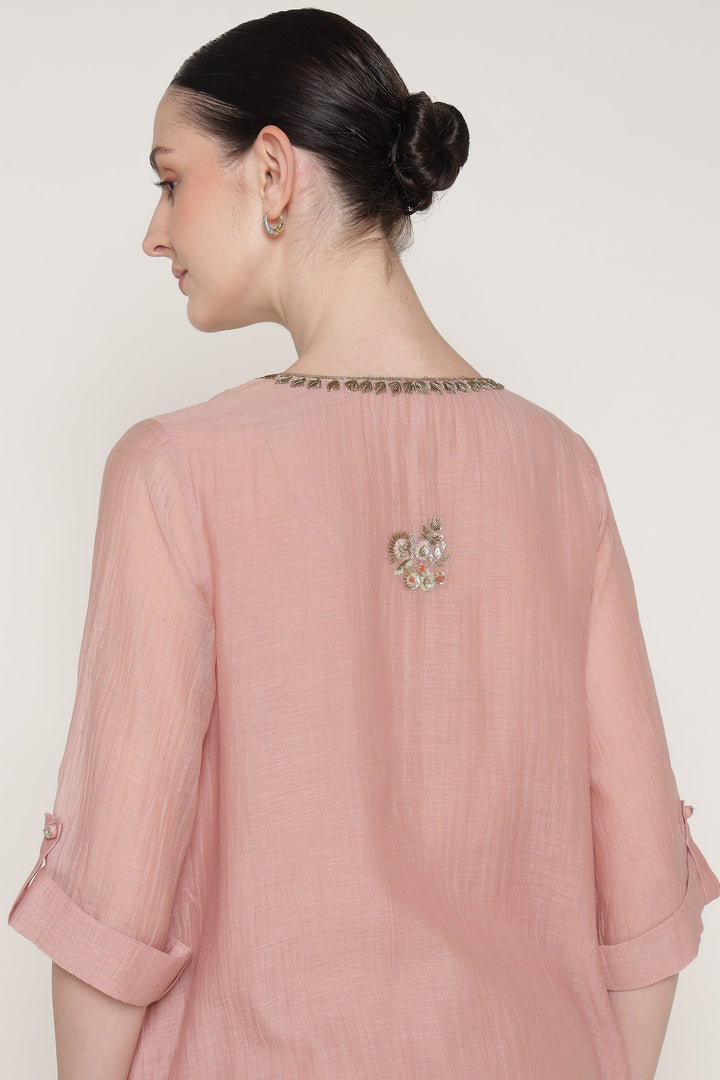 Woman wearing a pink outfit with intricate detailing on a white background