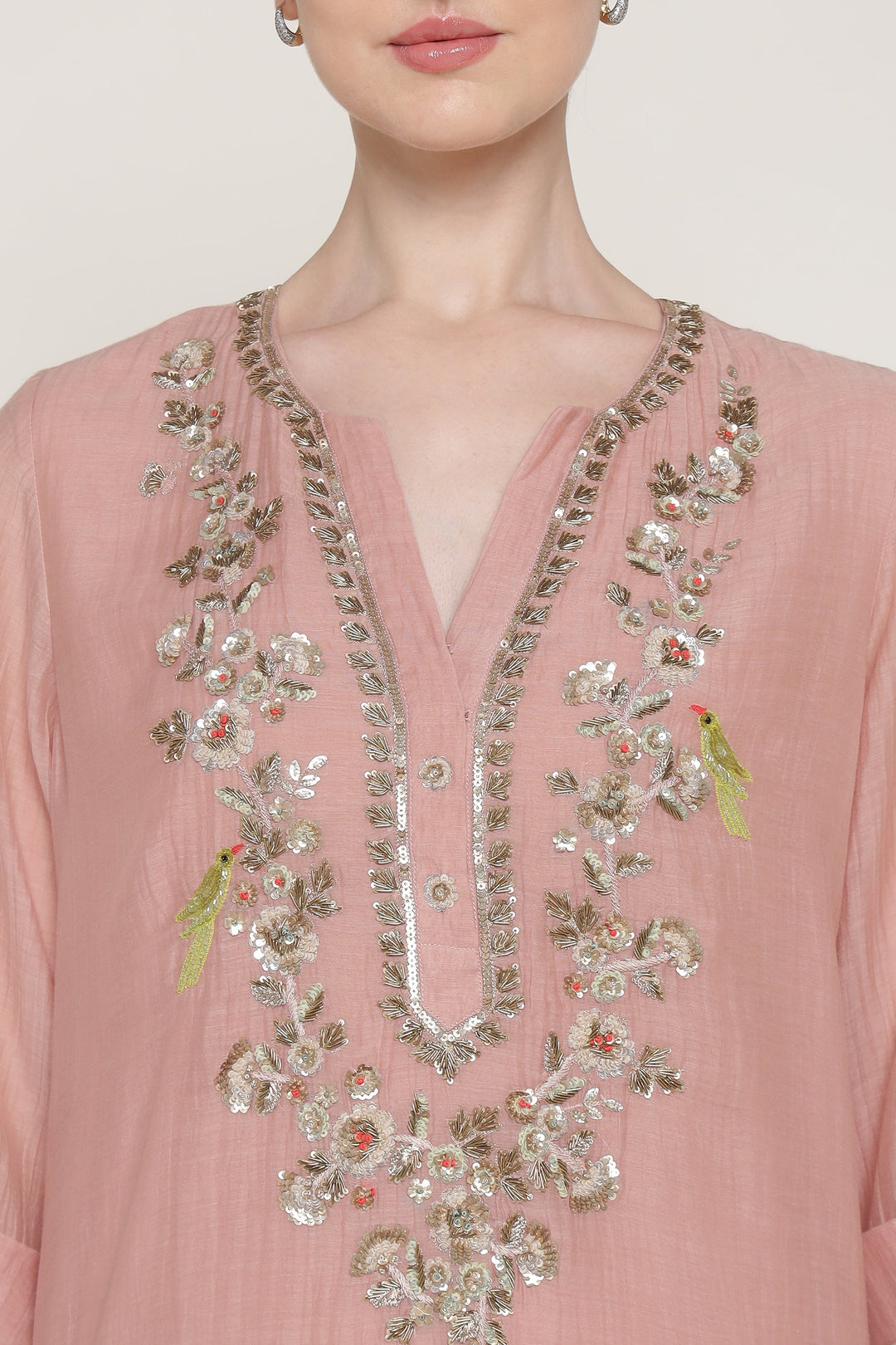 Pink blouse with intricate gold embroidery on a plain background