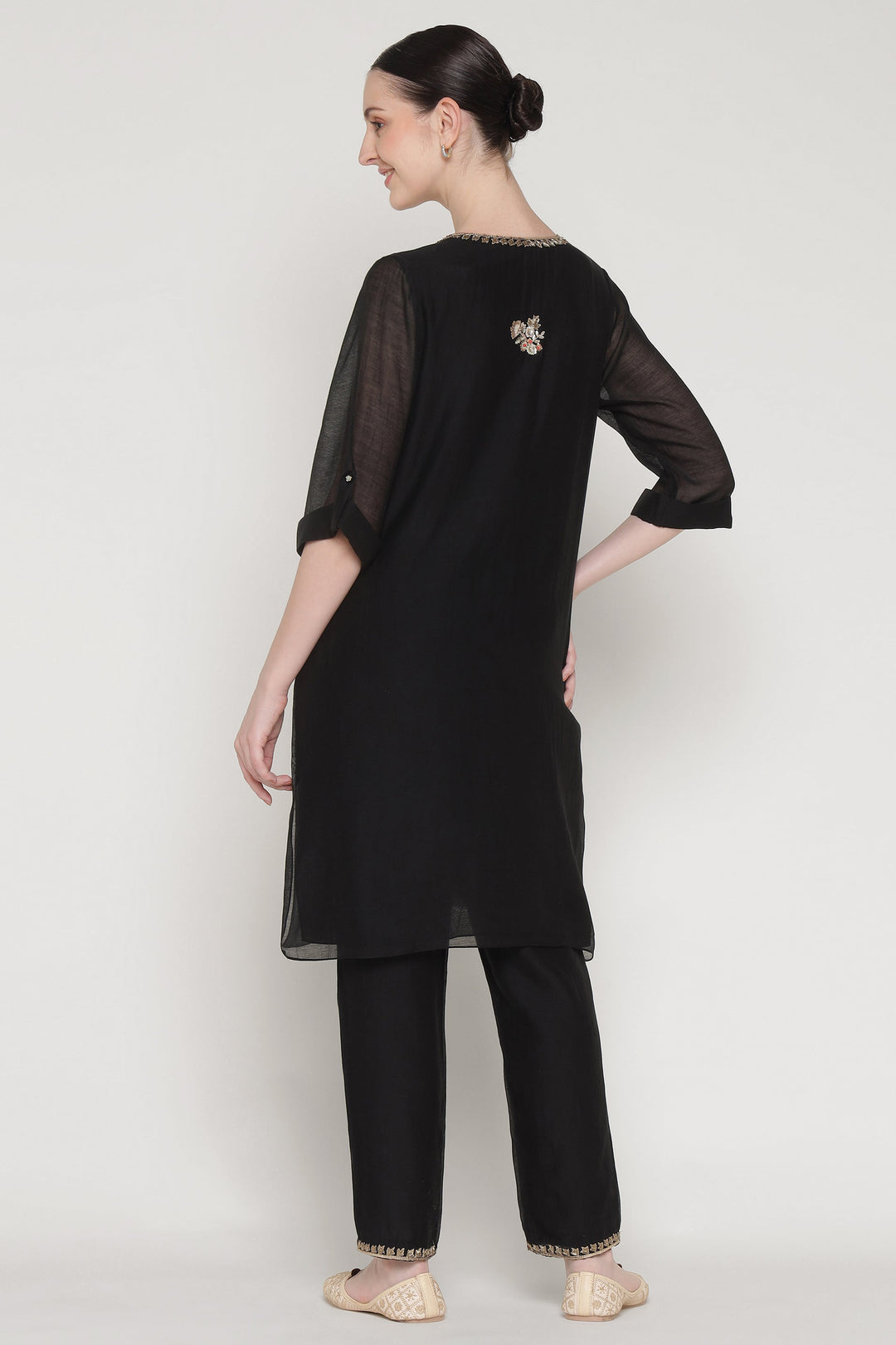 Woman wearing a black outfit with sheer sleeves on a white background