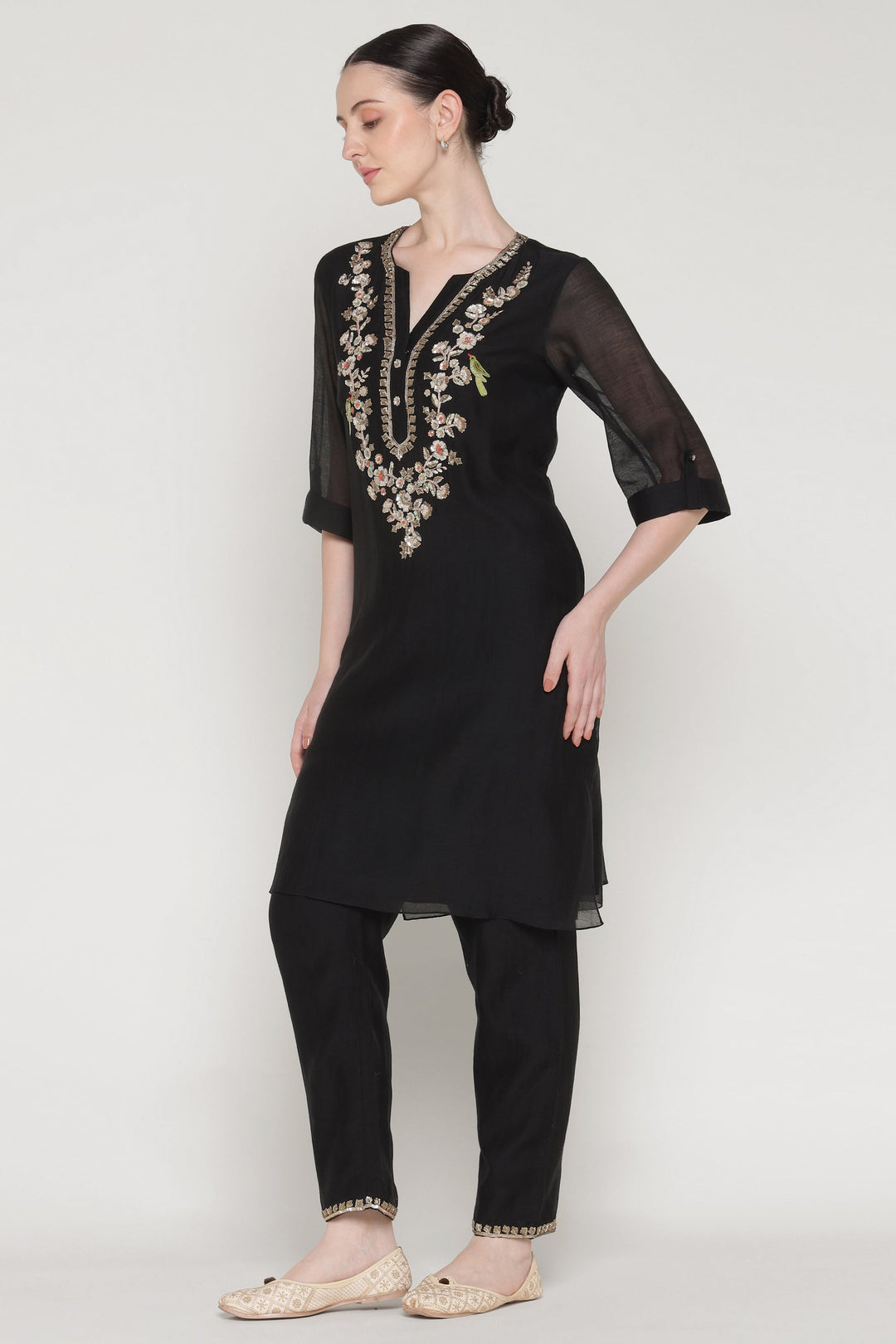 Woman wearing a black outfit with embroidery on a white background