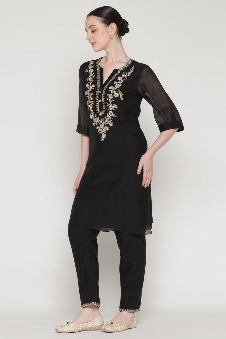 Woman wearing a black outfit with embroidery on a white background