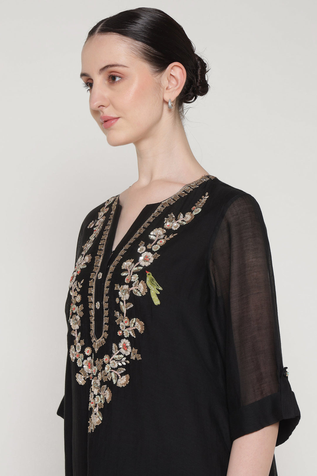 Woman wearing a black outfit with floral embroidery on a white background