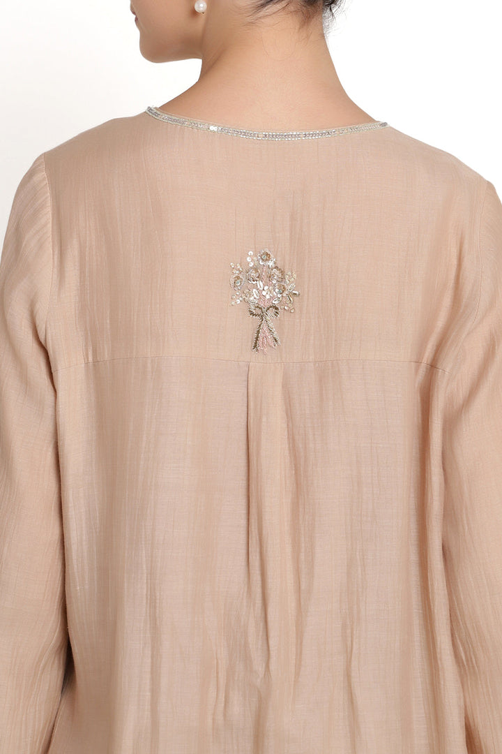 Beige outfit with floral embellishment on a white background