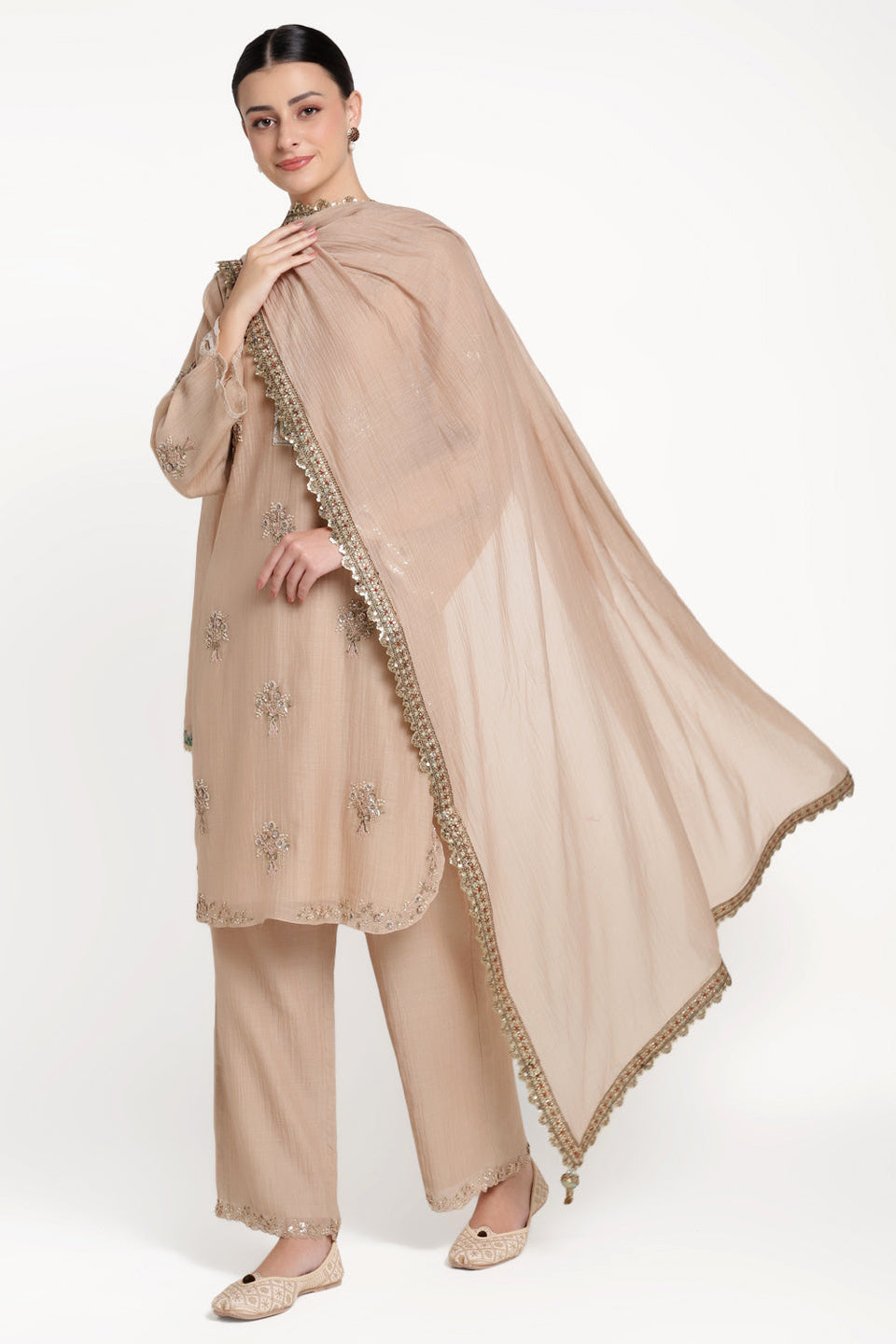 Woman wearing a beige traditional outfit with a matching dupatta on a white background