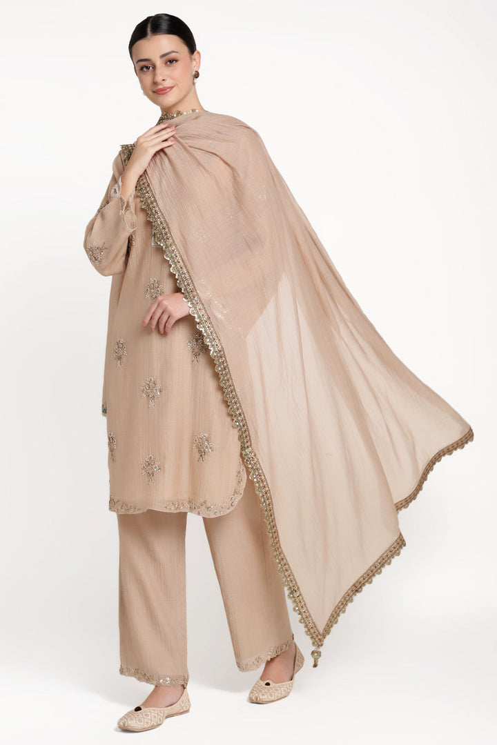 Woman wearing a beige traditional outfit with a matching dupatta on a white background