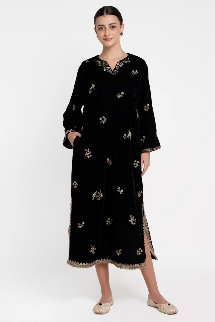 Woman wearing a black dress with floral embroidery on a white background