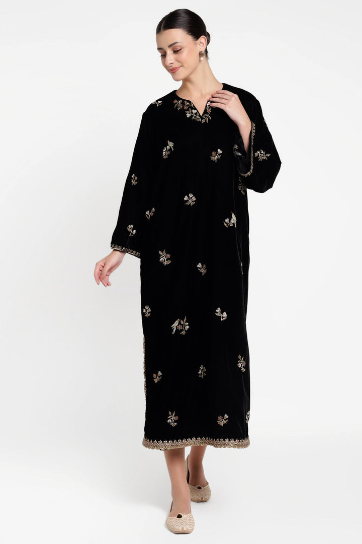 Woman wearing a black embroidered dress on a white background