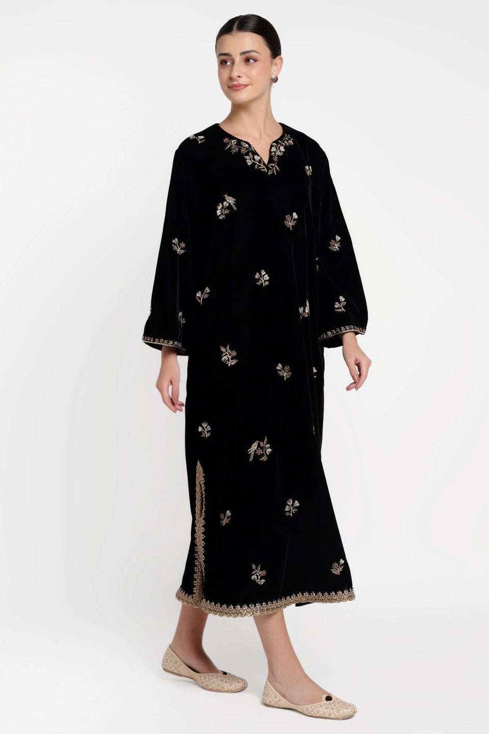 Woman wearing a black dress with floral embroidery on a white background