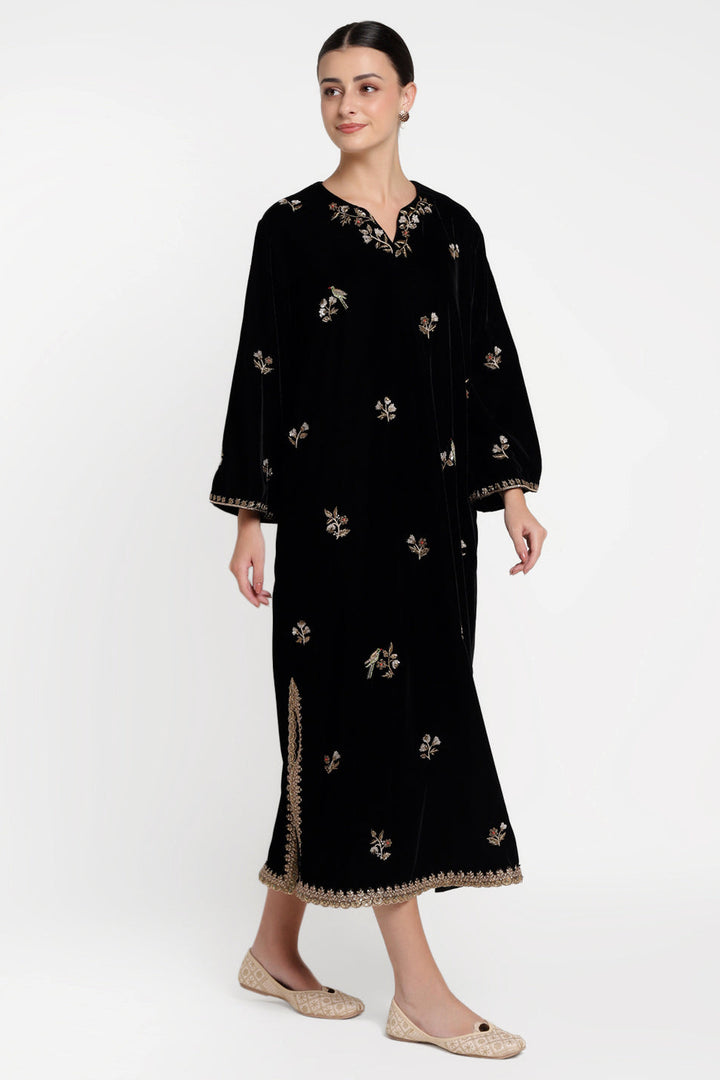 Woman wearing a black dress with floral embroidery on a white background