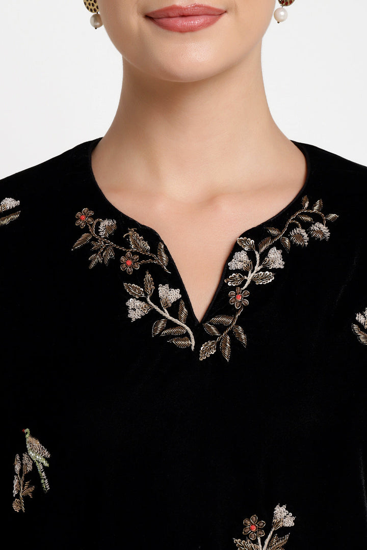 Black embroidered top with floral patterns on a white background