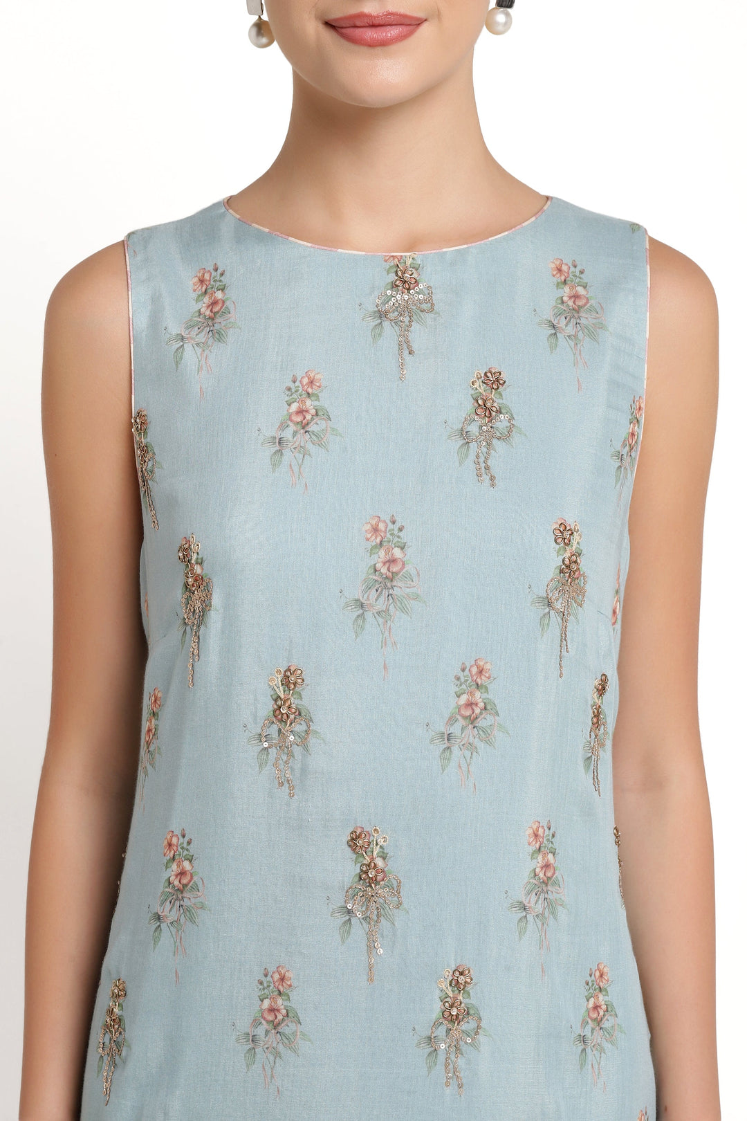 Light blue sleeveless top with floral patterns worn by a model on a white background