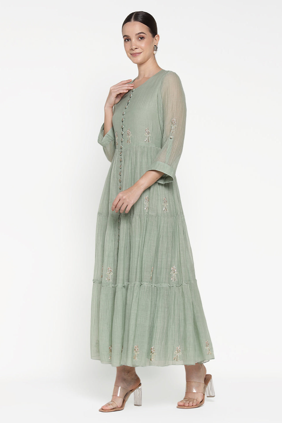 Woman wearing a light green dress with embroidery on a white background