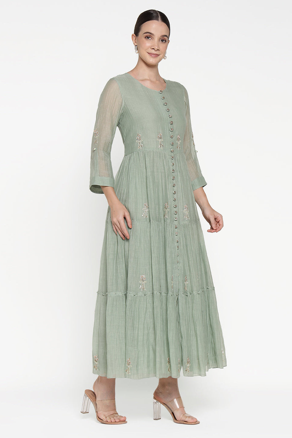 Woman wearing a light green dress with floral embroidery on a white background