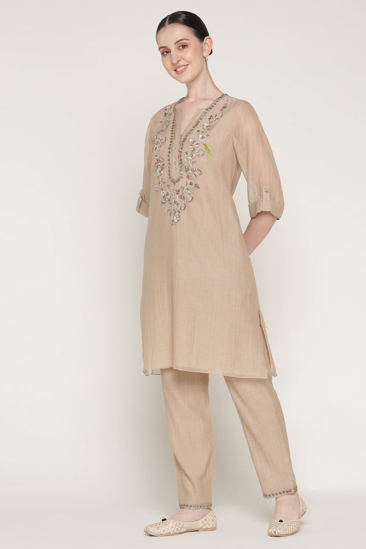 Woman wearing a beige kurta with embroidery on a white background