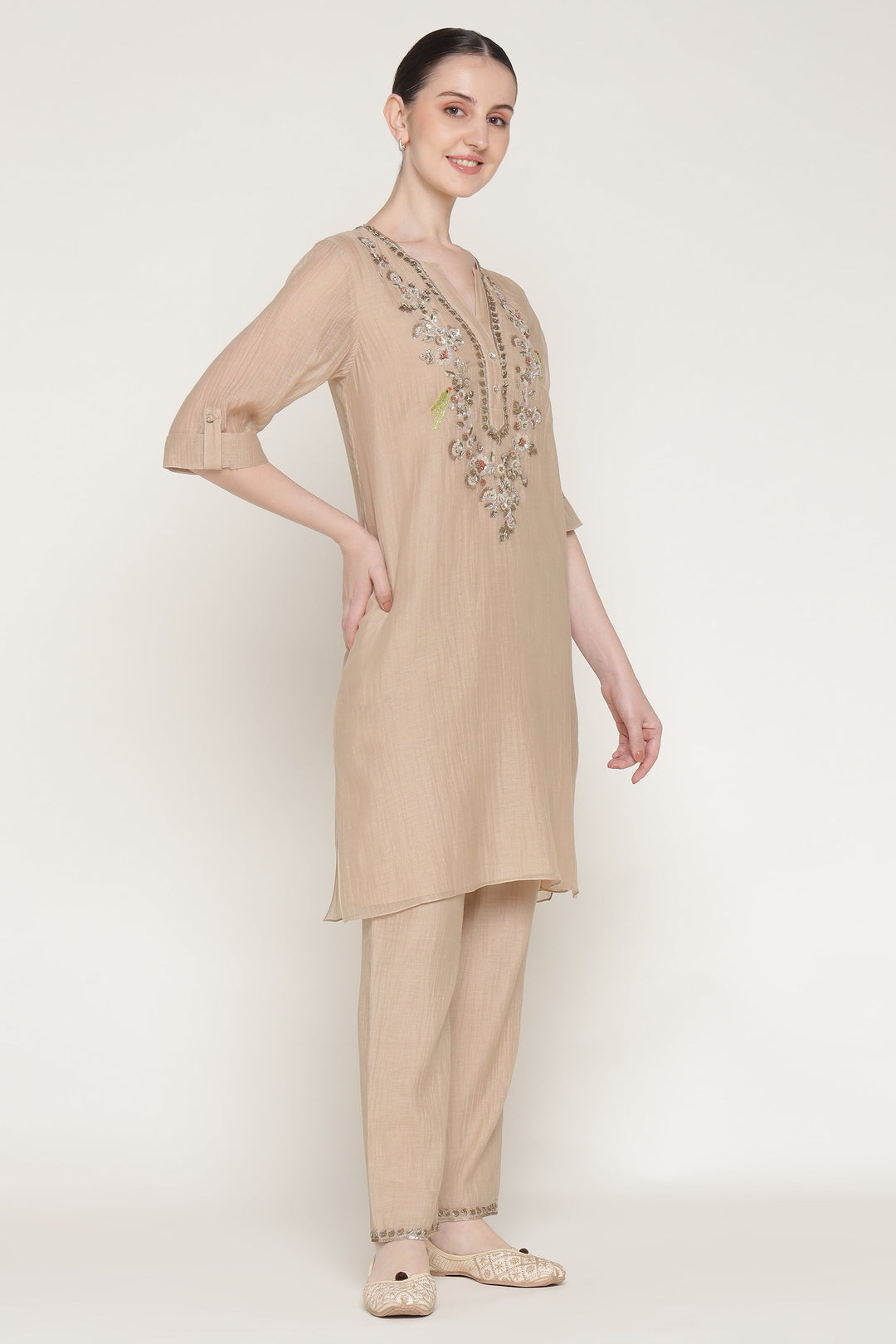 Woman wearing a beige kurta with embroidery on a white background