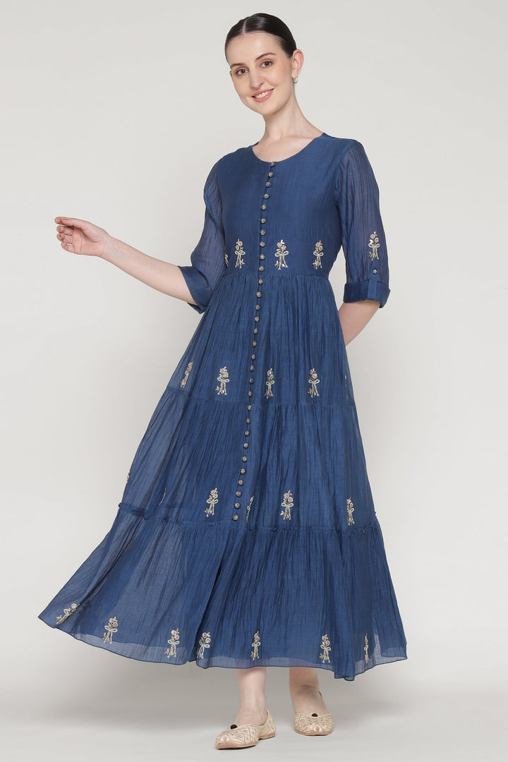 Woman wearing a blue dress with floral embroidery on a white background