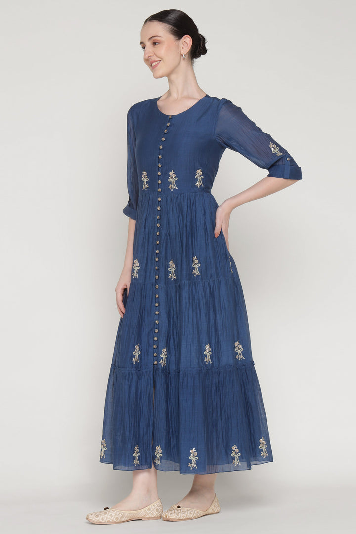 Woman wearing a blue dress with floral embroidery on a white background