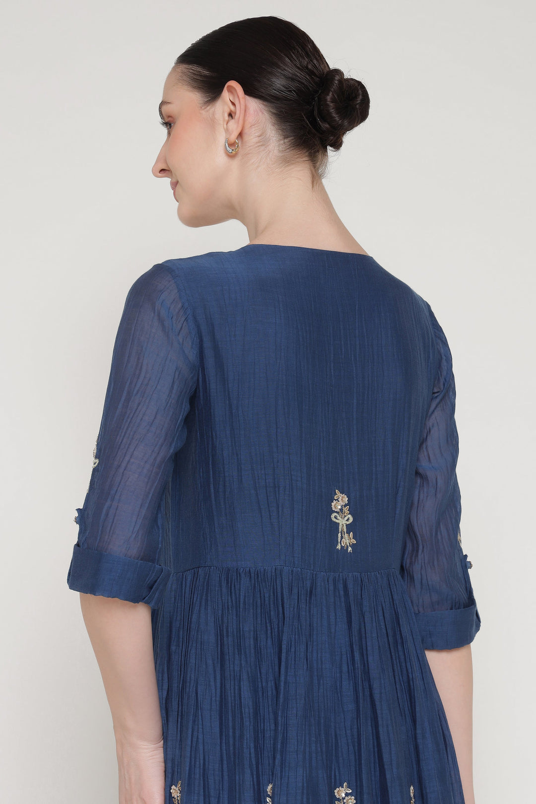 Woman wearing a blue dress with intricate detailing on a white background