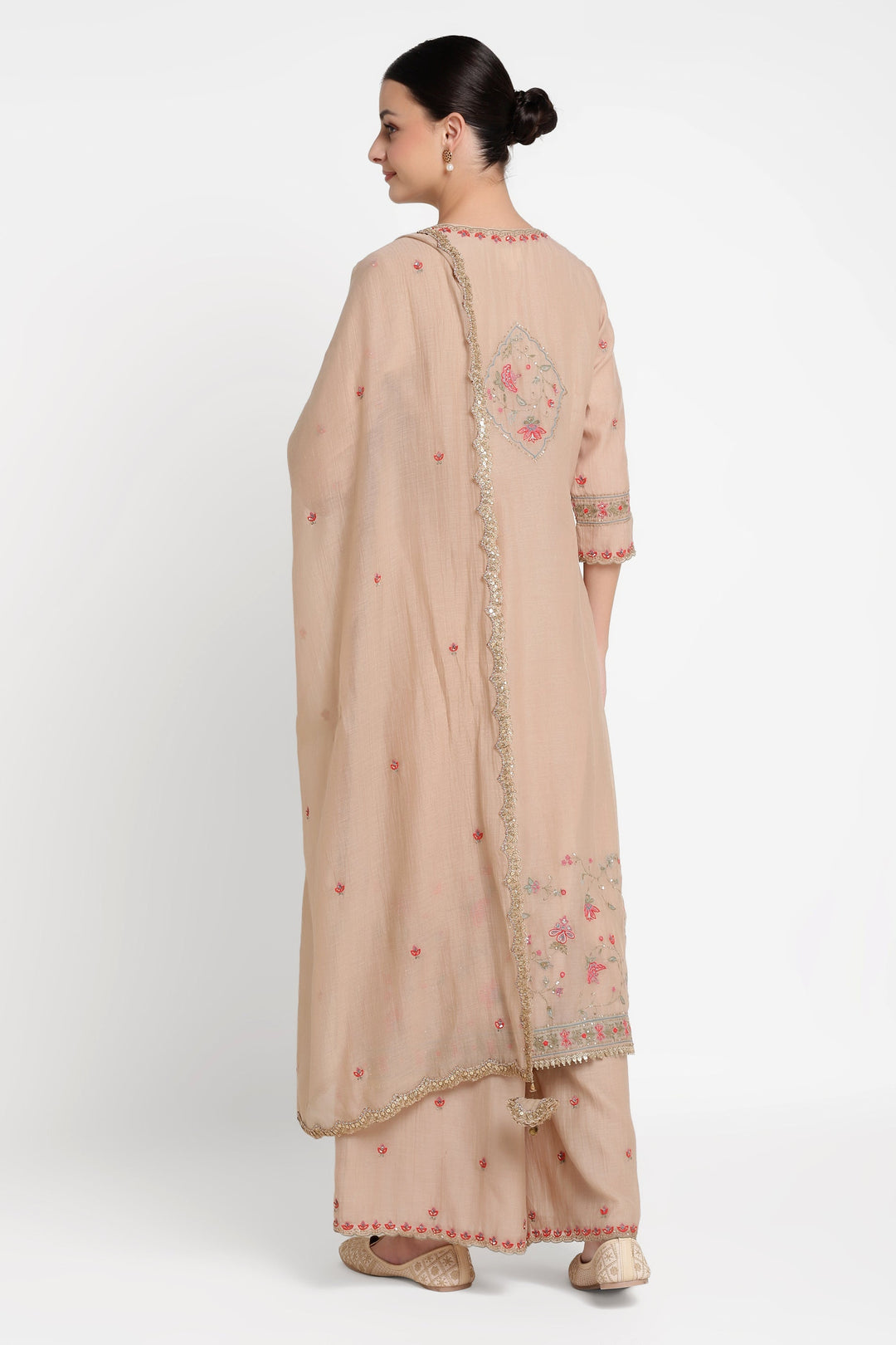 Woman wearing a beige traditional outfit with floral embroidery on a white background