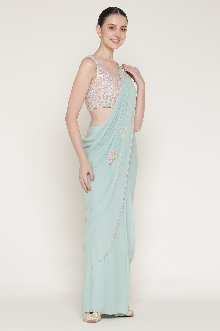 Woman wearing a light blue saree with a white blouse on a white background