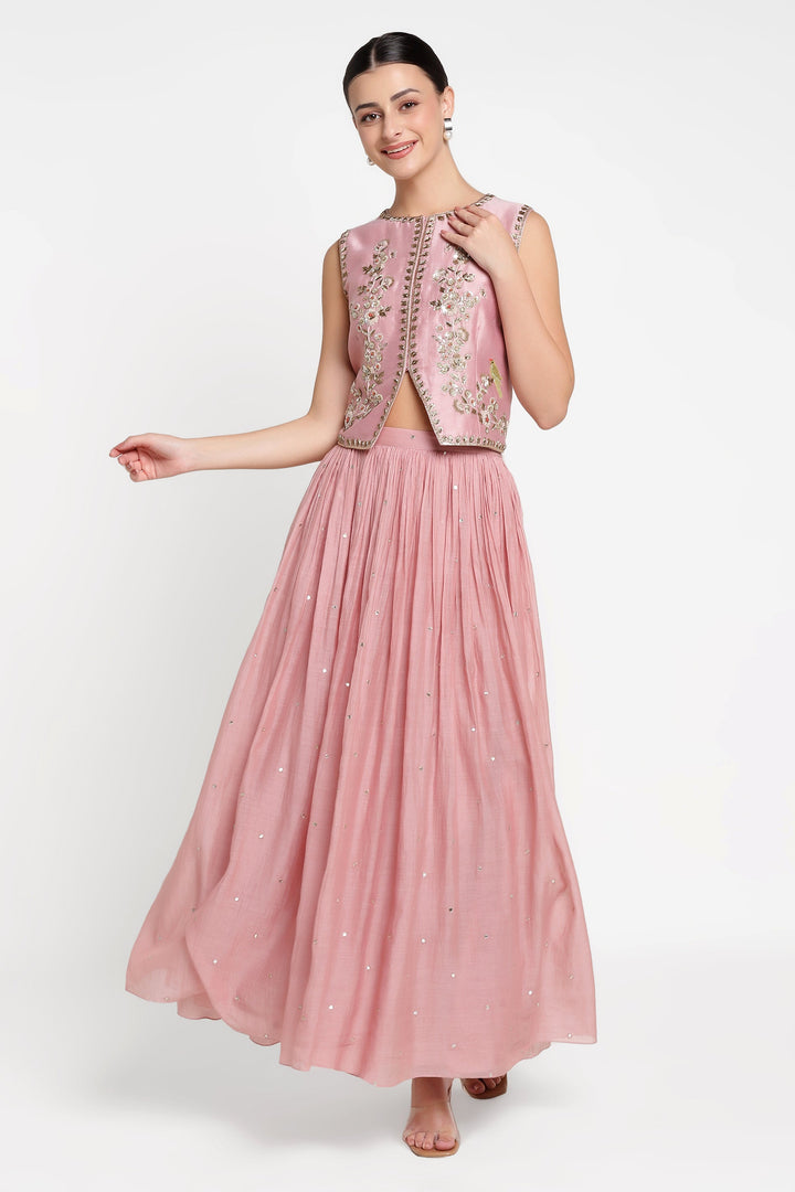 Woman wearing a pink embroidered outfit on a white background