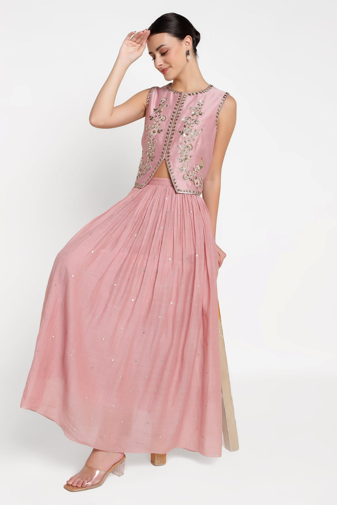 Woman wearing a pink dress with intricate detailing on a white background