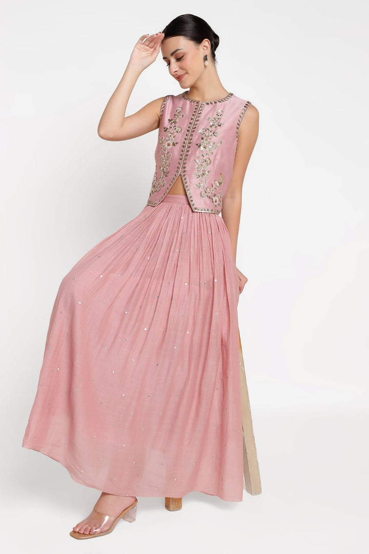 Woman wearing a pink dress with intricate detailing on a white background