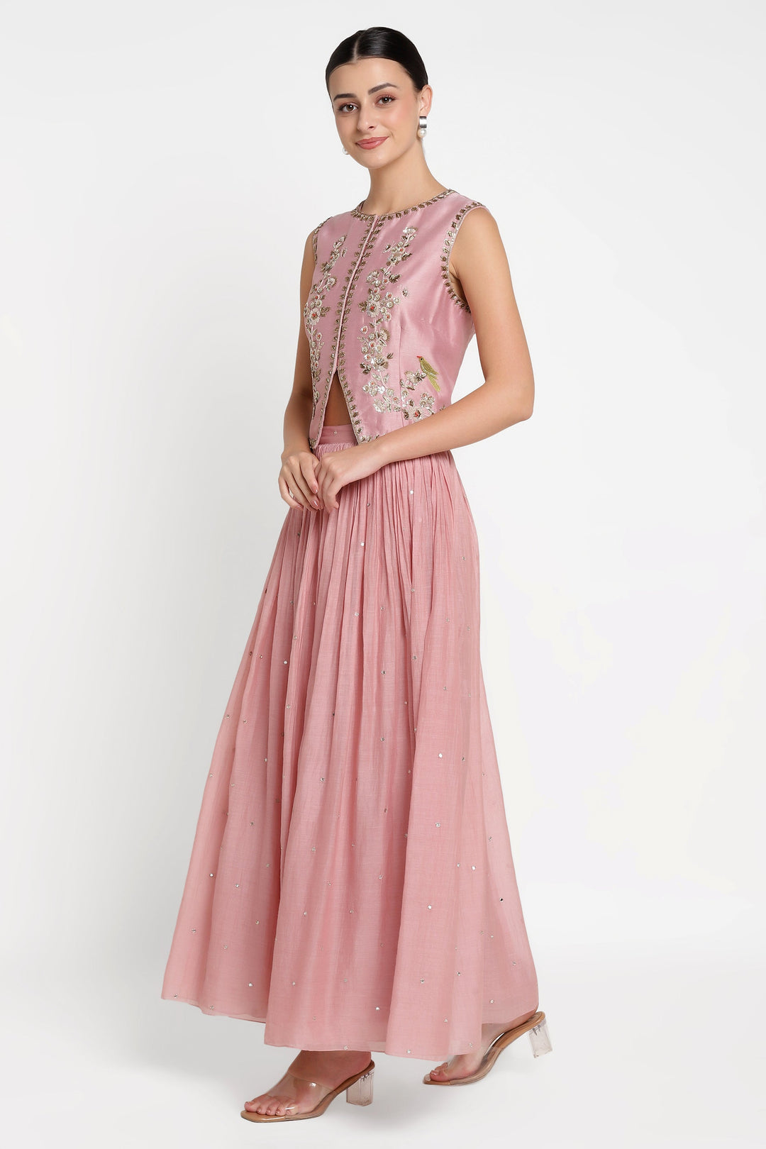 Woman wearing a pink embroidered dress on a white background