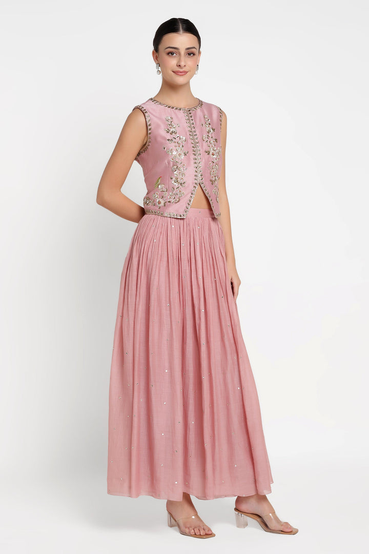 Woman wearing a pink embroidered dress on a white background