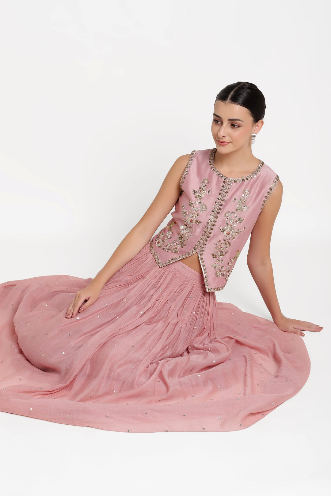 Woman wearing a pink traditional outfit with intricate designs on a white background