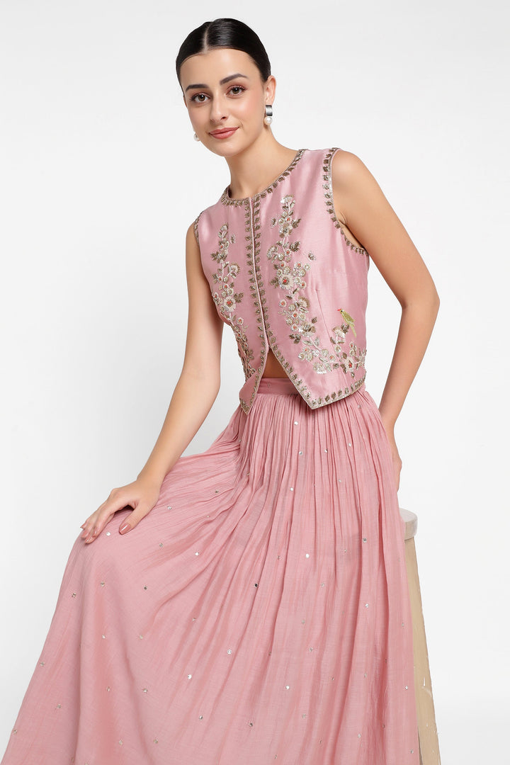 Woman wearing a pink embroidered outfit on a white background