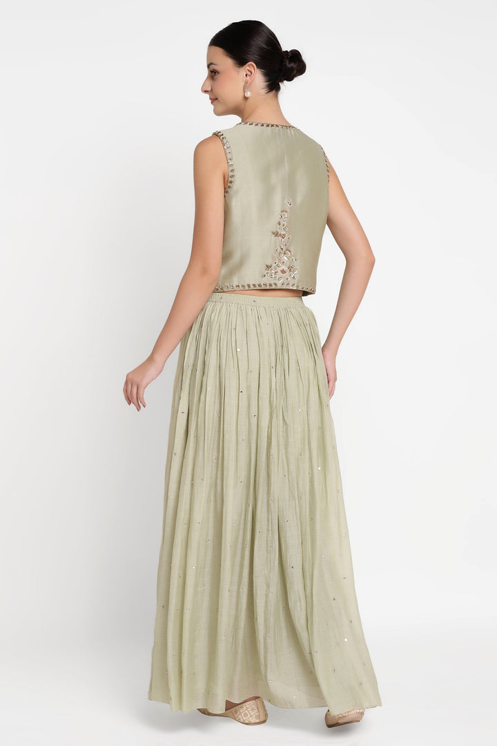 Woman wearing a light green traditional outfit with an embroidered top on a white background