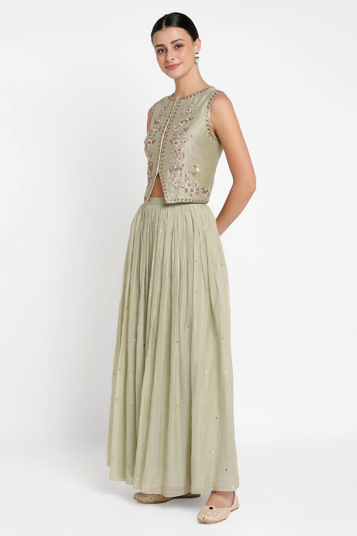 Woman wearing a light green traditional outfit with a white background