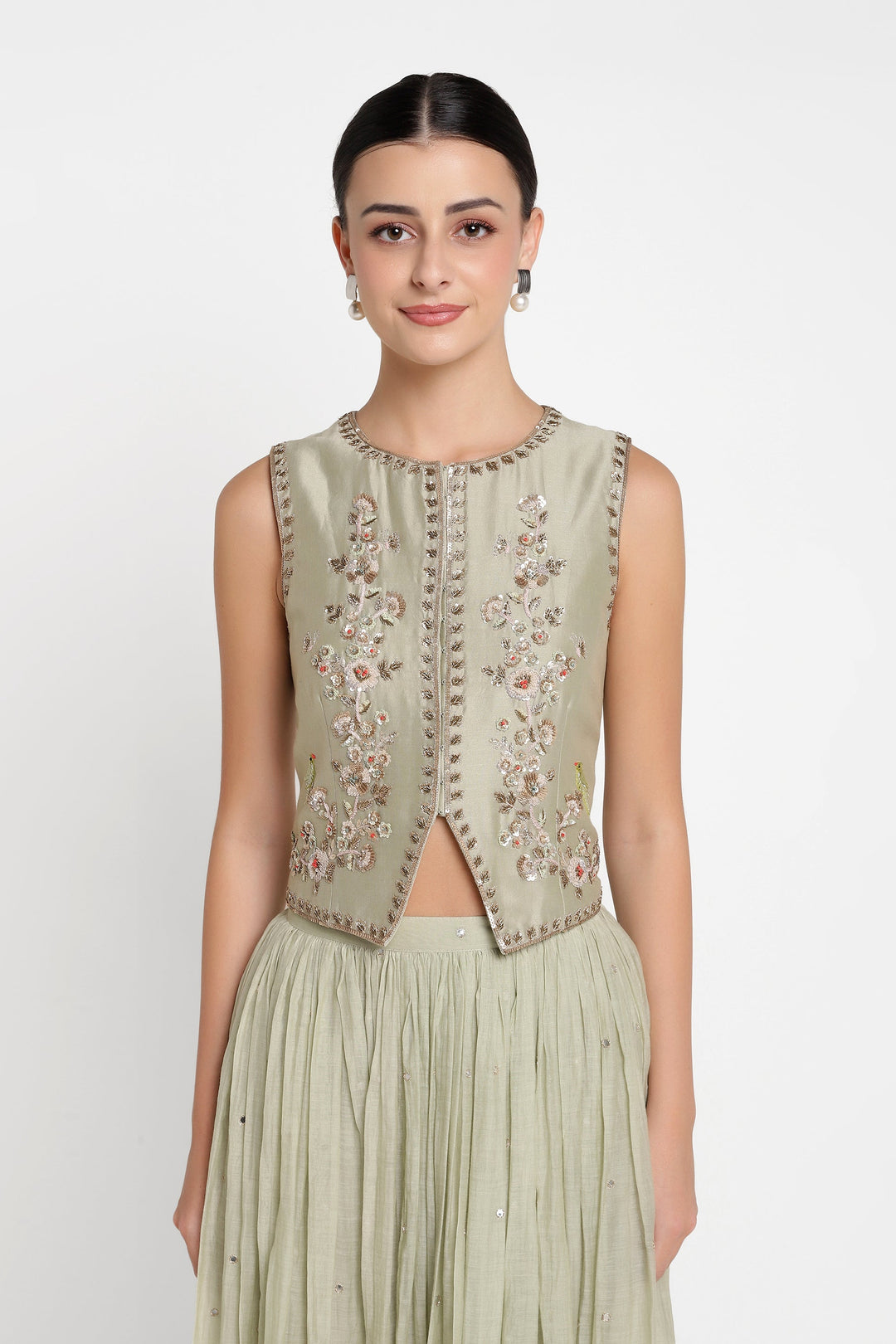 Woman wearing a light green embroidered top and skirt set on a white background