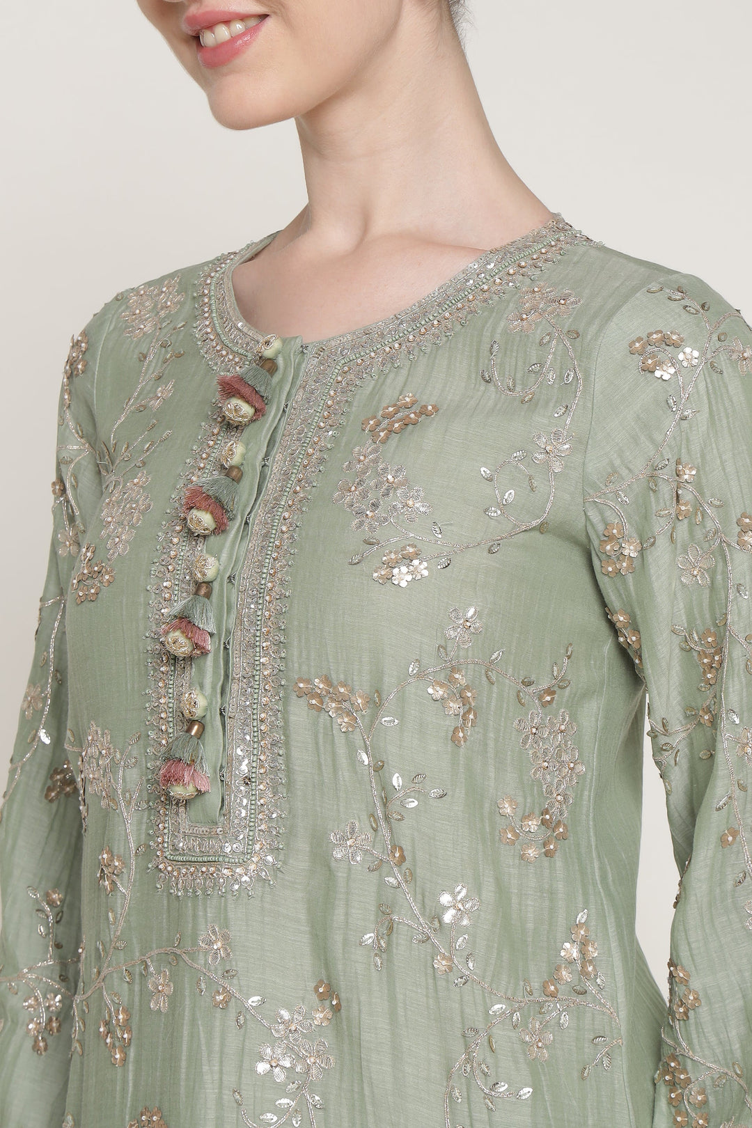 Light green embroidered traditional outfit on a plain background