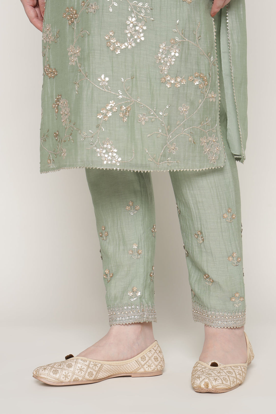 Light green traditional outfit with floral embroidery on a white background